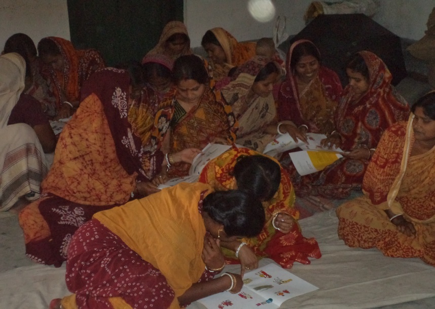Rural women reading awareness leaflets on health and rights